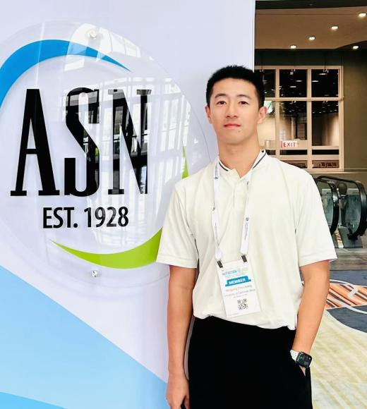 Troy Huang standing beside an American Society for Nutrition banner